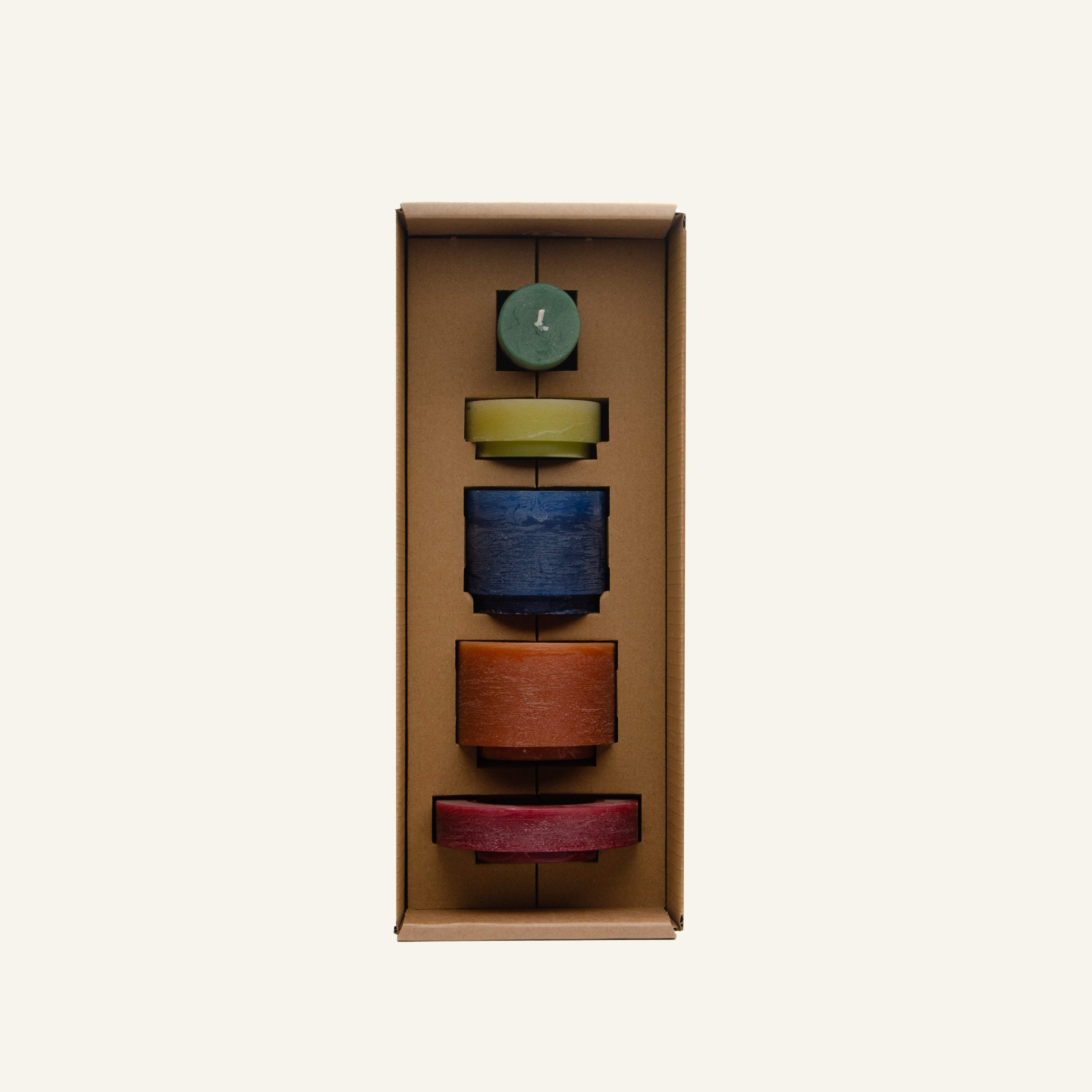 Een set van vijf kaarsen in verschillende kleuren en formaten, netjes verpakt in een kartonnen doos met op maat gemaakte vakken. De kaarsen zijn groen, geel, blauw, bruin en rood en zijn gestapeld in een verticale opstelling.